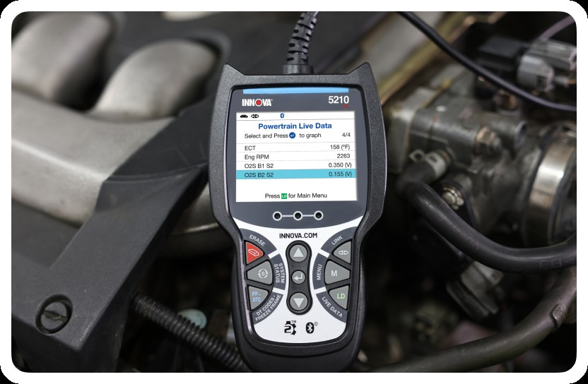 Close-up of a person using a car diagnostic scanner tool on a vehicle's OBD-II port