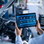 Mechanic using a tablet with car diagnostics software to inspect a vehicle.