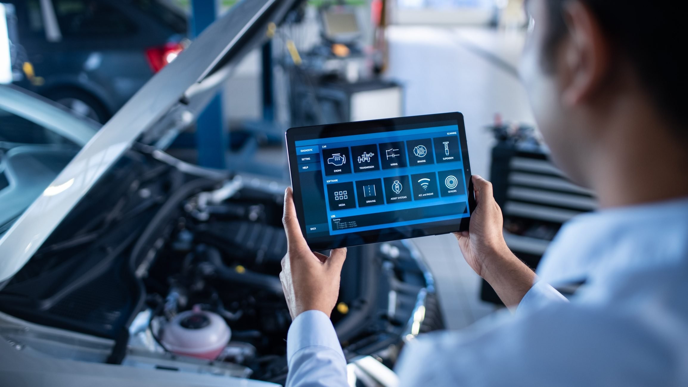 Mechanic using a tablet with car diagnostics software to inspect a vehicle.