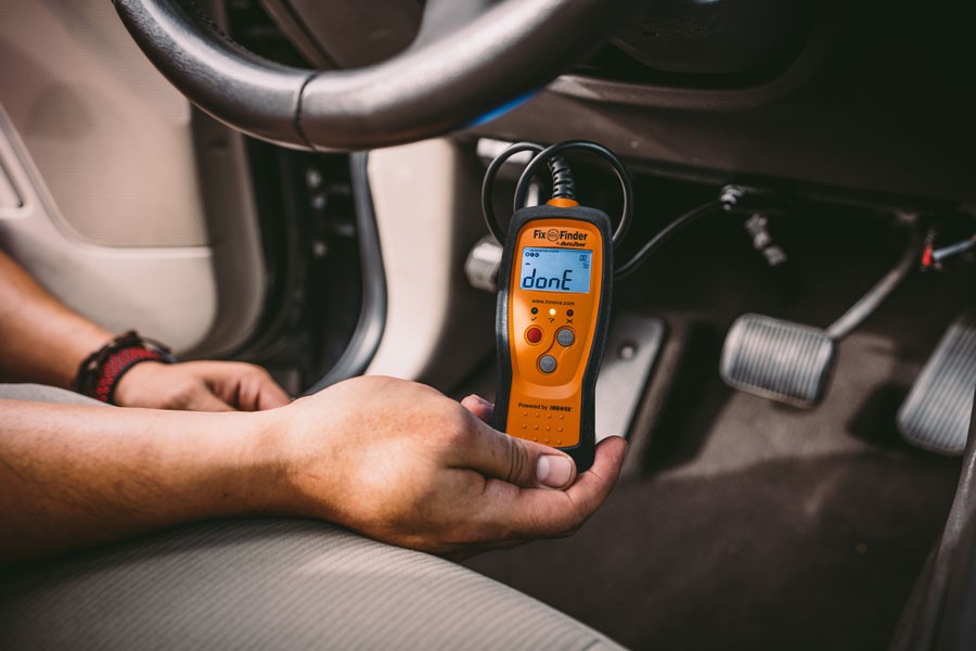 Connecting OBD2 scanner to car diagnostic port under dashboard