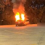 Intense flames engulf a car in the Walmart parking lot in Crystal Lake, Illinois, during a fatal vehicle fire incident.