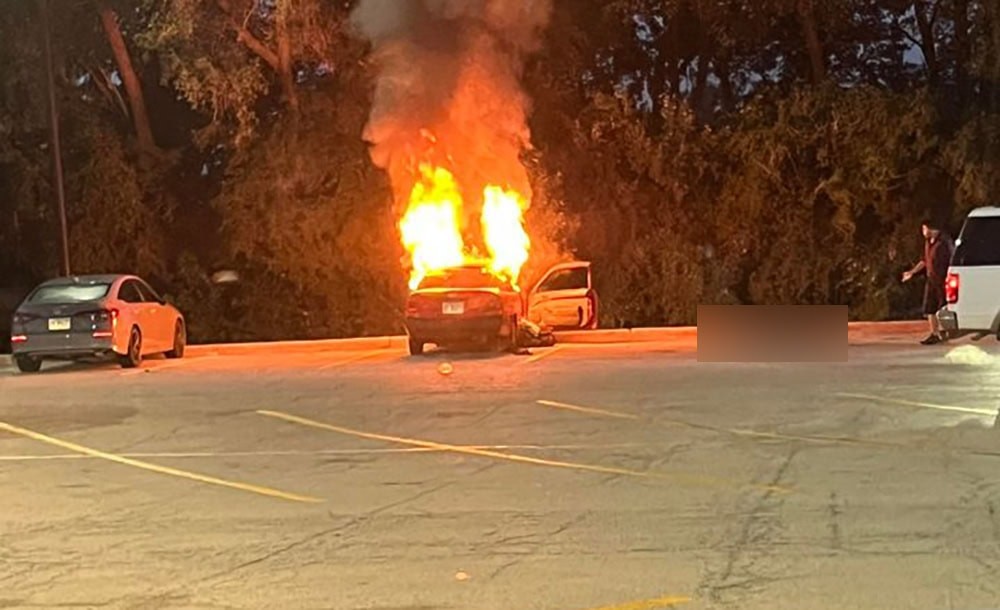 Intense flames engulf a car in the Walmart parking lot in Crystal Lake, Illinois, during a fatal vehicle fire incident.