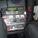 Police scanner mounted in a car's center console, demonstrating a potential installation location when using a car radio antenna for improved reception.