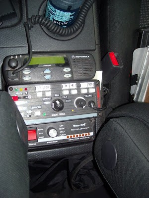 Police scanner mounted in a car's center console, demonstrating a potential installation location when using a car radio antenna for improved reception.